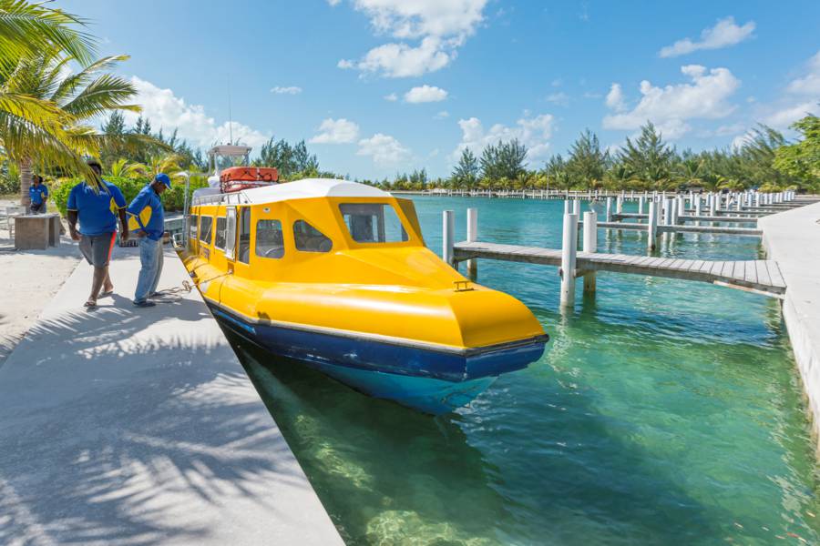A small ferry boat docked at Sandy Point, North Caicos, surrounded by calm turquoise waters and a clear blue sky, ready for island transfers.